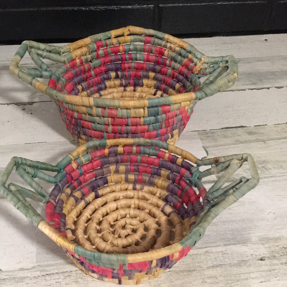 Set of two woven multi colored rope look circular baskets with handles.